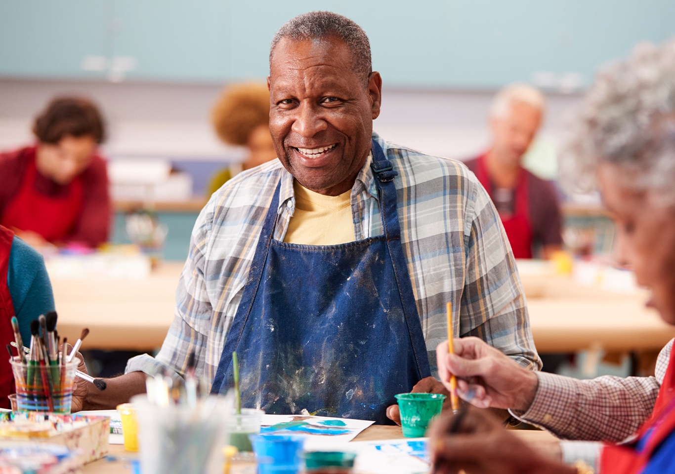 A senior enjoying a painting activity alongside fellow participants at a SarahCare adult day health center
