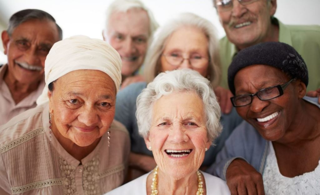 A diverse group of smiling seniors together at a SarahCare adult day health center