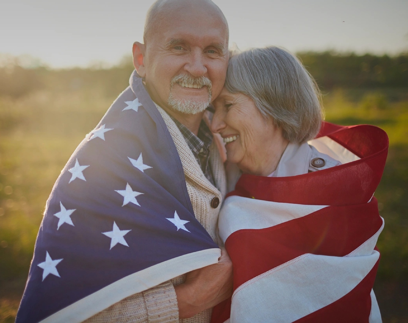 A senior Veteran and his wife wrapped together in an American flag